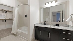 Une salle de bain moderne avec une douche, un lavabo et un grand miroir.