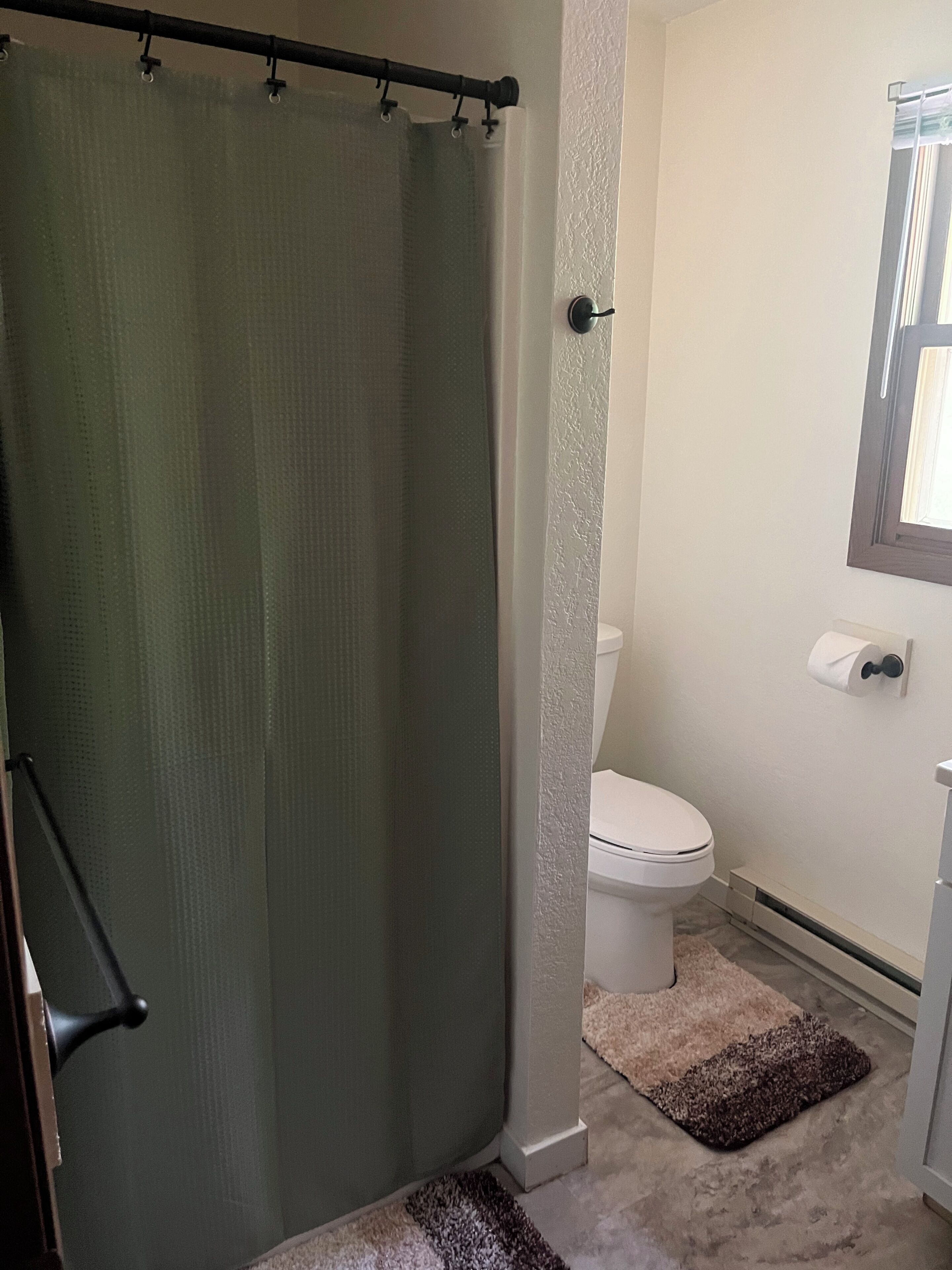 Un bagno con tenda da doccia, wc e porta asciugamani.