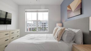 A bedroom with a bed, a TV, a window, and a lamp. - Landing | Beautiful 1BD, Clubhouse, Gym (Kissimmee)
