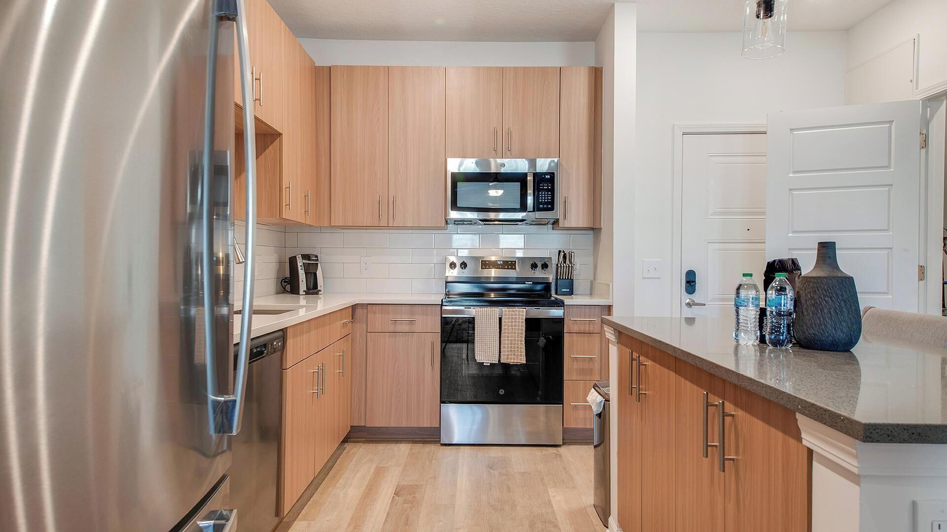 Una cocina moderna con electrodomésticos de acero inoxidable, armarios de madera y encimera de granito.