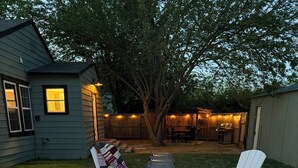 Um quintal com uma lareira, quatro cadeiras Adirondack e um deck de madeira.