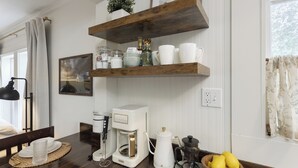 Uma cozinha com cafeteira, chaleira, liquidificador e uma tigela de limões na bancada.