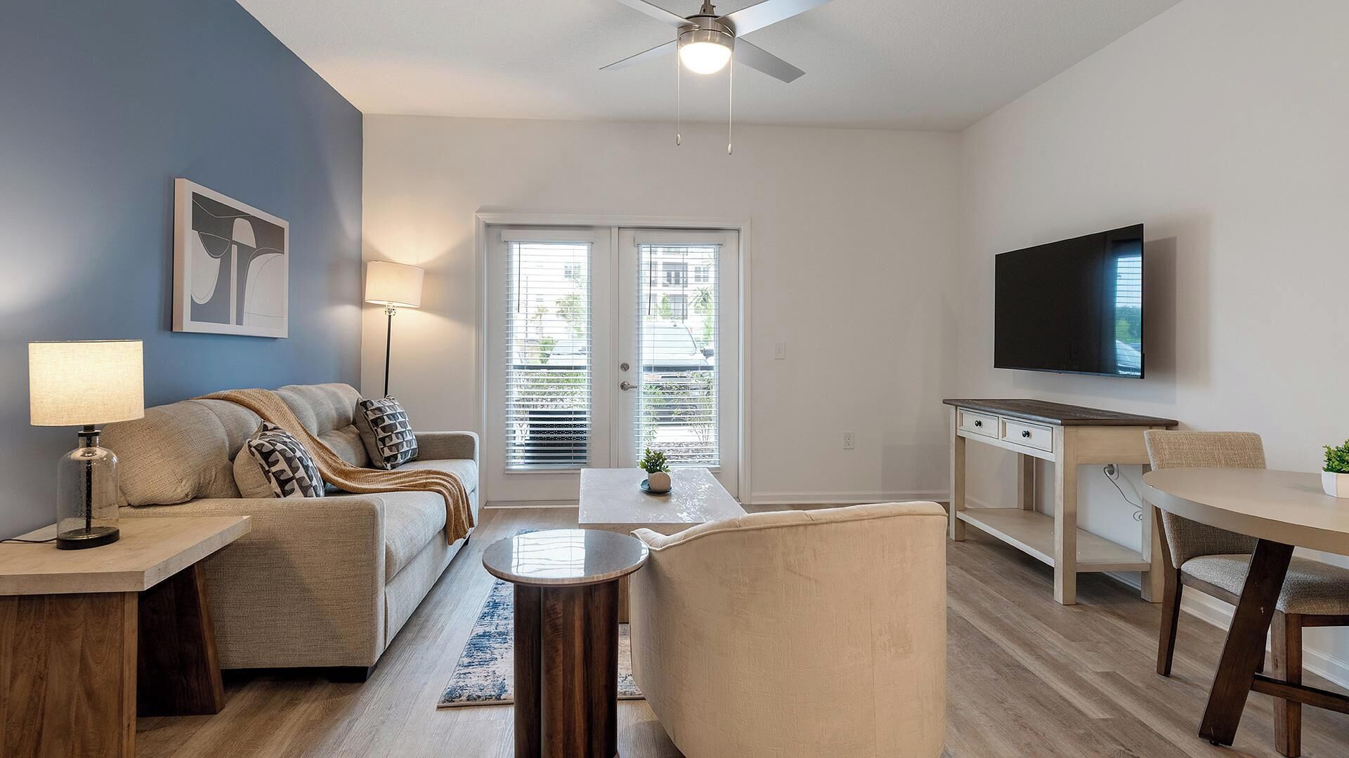 A living room with a sofa, a coffee table, a TV, and a dining area with a table and chairs.