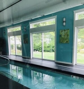 Ein Swimmingpool mit klaren Glaswänden, Blick ins Grüne und ein gefliestes Becken.