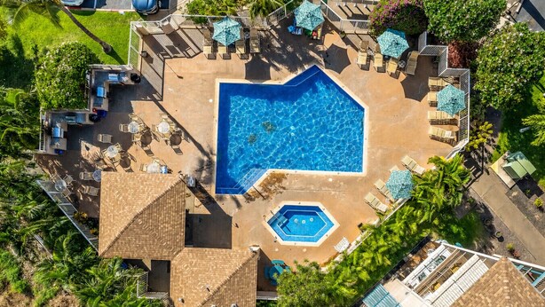 Luftaufnahme eines Resorts mit einem großen zentralen Pool, mehreren kleineren Pools und schattigen Liegebereichen mit Sonnenschirmen.