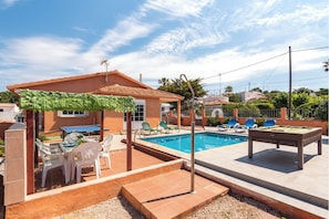 A pool area with a table and chairs, a covered seating area, and a poolside lounge.