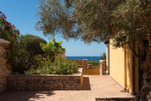 A stone pathway leading to a gate, surrounded by lush greenery and a view of the sea. - Villa Lamar - Three Bedroom Villa, Sleeps 6 (Alayor)