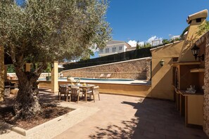 An outdoor patio with a pool, seating area, and a stone wall. - Villa Lamar - Three Bedroom Villa, Sleeps 6 (Alayor)