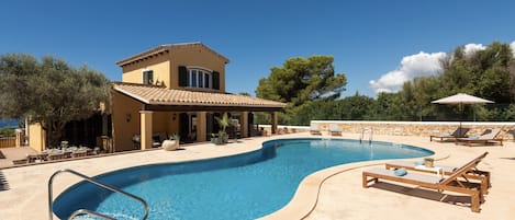 A swimming pool with lounge chairs and a building with a tiled roof.