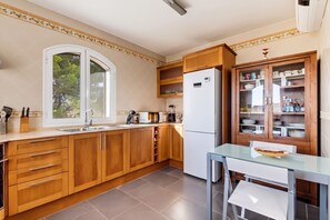 Eine moderne Küche mit Holzausstattung, einer eingebauten Mikrowelle und einem Kühlschrank.