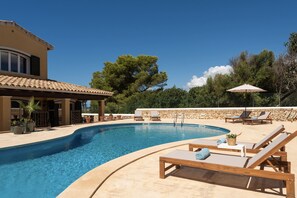 A swimming pool with lounge chairs and umbrellas, surrounded by a stone wall and trees. - Villa Lamar - Three Bedroom Villa, Sleeps 6 (Alayor)