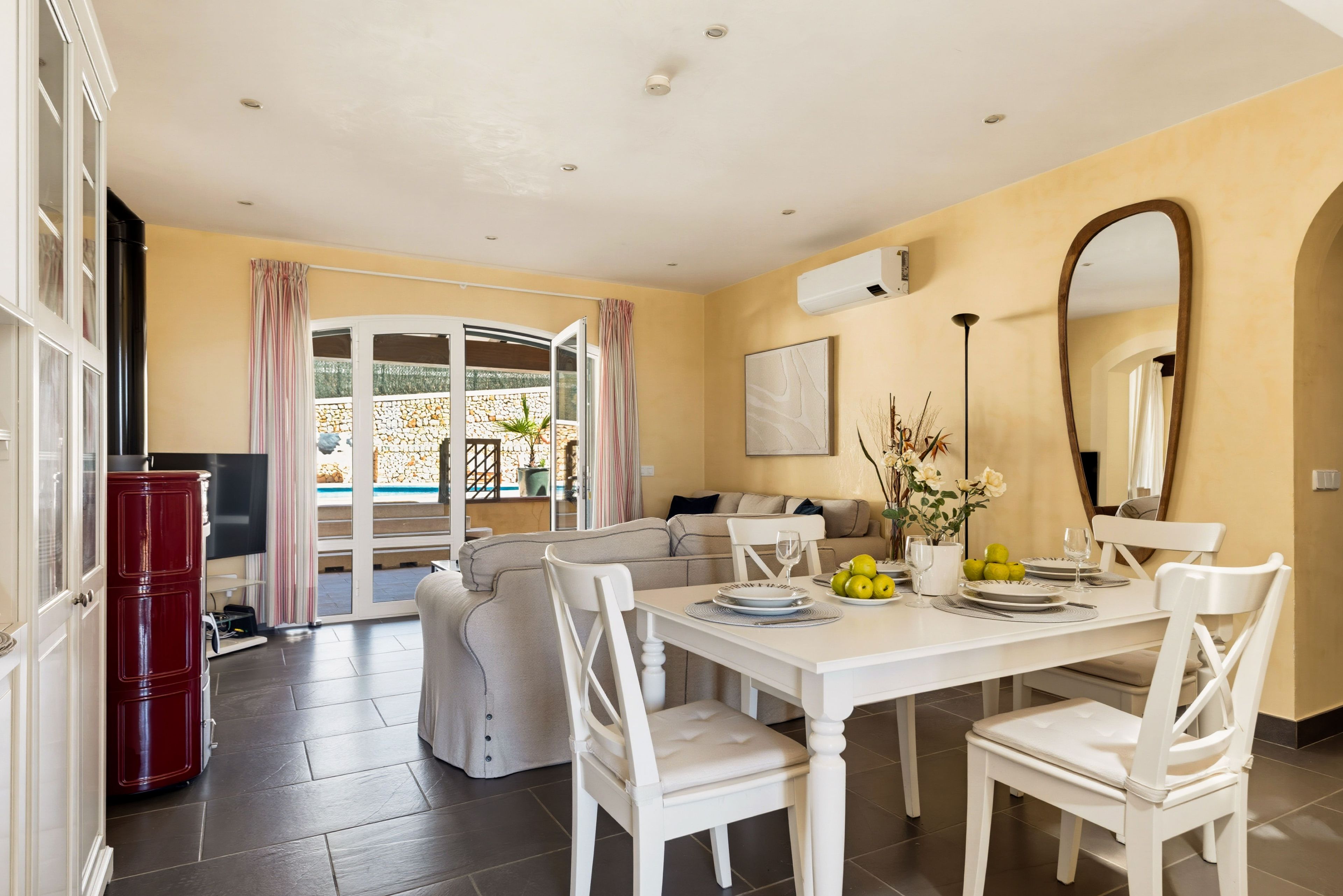 A dining area with a table set for two, a sofa, and a TV in the background.