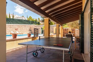 Una mesa de ping pong con ruedas, piscina y mobiliario exterior.