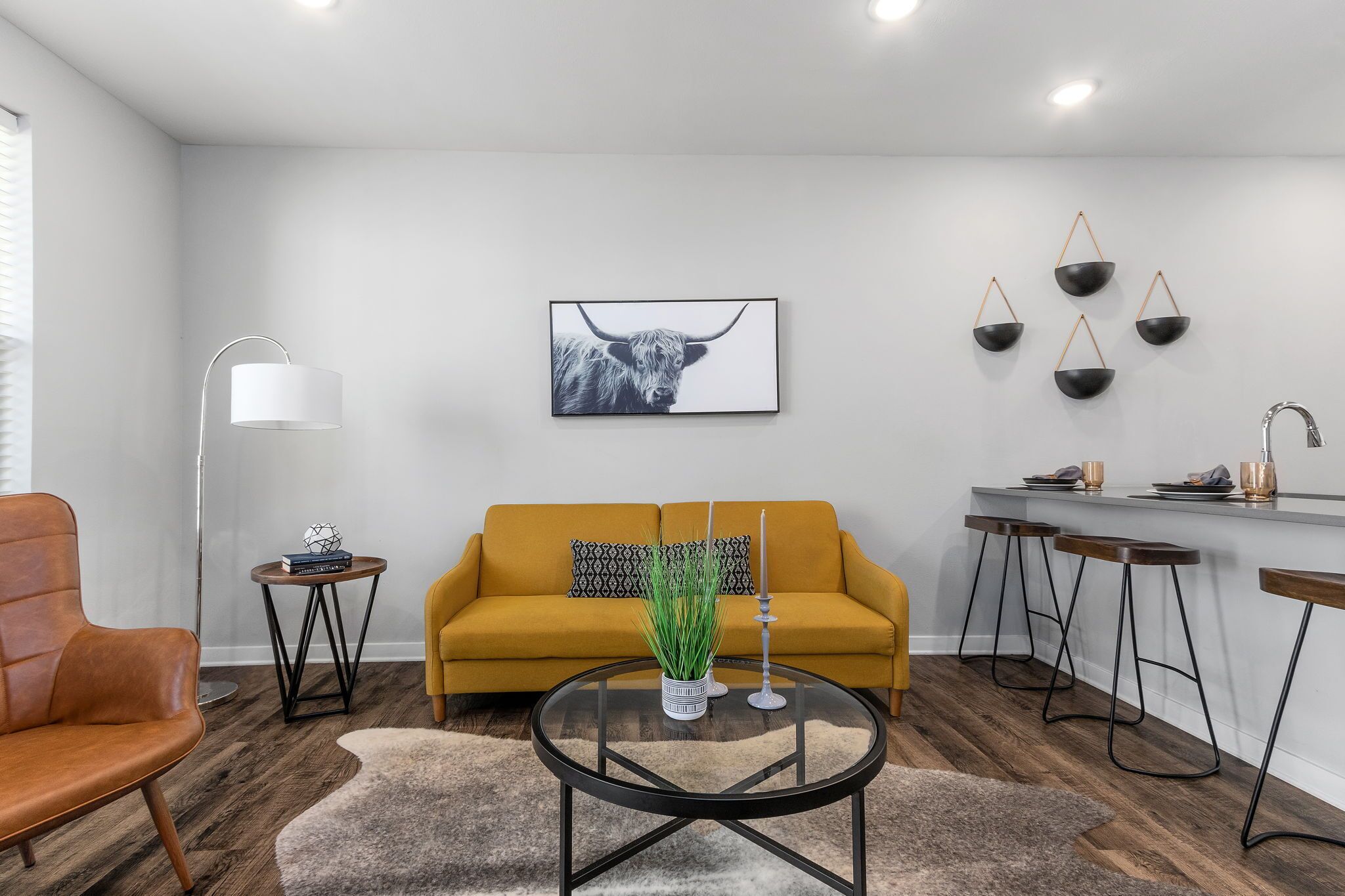 Un salon moderne avec un canapé, une table basse et un coin repas équipé de tabourets.