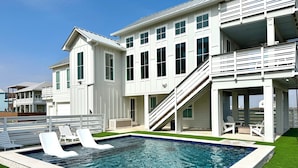 Une grande maison moderne dotée d’une piscine, de nombreux balcons et d’un espace extérieur aménagé et couvert.