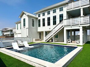 Una casa grande y moderna con piscina, varios balcones y una zona de estar cubierta al aire libre.