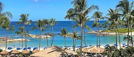 A beach resort with palm trees, a pool, and beach umbrellas.