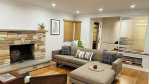 Una sala de estar con chimenea de piedra, un sofá, una mesa de centro y una estantería.