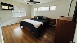 Un dormitorio con cama, ventilador de techo y ventana con persianas.