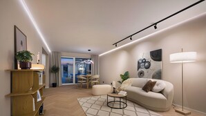 A modern living room with a sofa, a coffee table, a floor lamp, and a bookshelf. - Modern 3BR apartment | Free parking | 10 min to centrum (Trondheim)