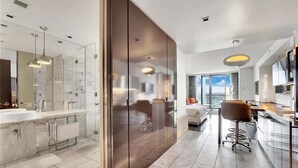 Ett modernt hotellrum med ett stort badrum, ett köksutrymme och en sittgrupp med utsikt.