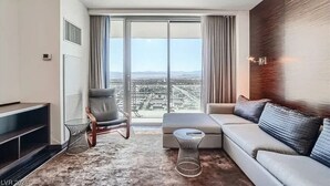 Un salon moderne comprenant un canapé, un fauteuil, une table basse et une grande fenêtre donnant sur la ville.