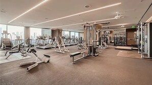 Une salle de sport moderne, dotée de divers appareils d’entraînement, de grandes fenêtres et d’un aménagement propre et spacieux.