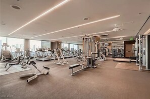 A modern gym with various exercise equipment, large windows, and a clean, spacious layout. - Incredible Penthouse Strip Views, Balcony Access (Las Vegas)