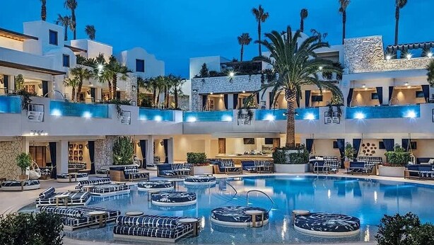 A hotel with a central pool surrounded by lounge areas, multiple floors with balconies, and palm trees. - Incredible Views 51st Floor High-Rise Studio -Balcony (Las Vegas)