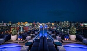 Eine Dachterrasse mit Blick auf die Stadt, ausgestattet mit einem Pool, Sitzbereichen und Pflanzkübeln.