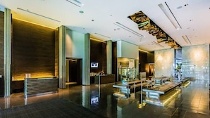 A spacious lobby with a reception desk, seating area, and a modern design with reflective flooring and vertical light fixtures. - High Floor Mountain-Views Studio BALCONY ACCESS (Las Vegas)