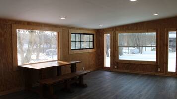A spacious room with large windows, a wooden bench, and a wooden table.