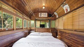 A wooden interior with a bed, windows, and a television. - Huge 5 Bed Party House: Pool/Renovated Tram/Bar/Games Room/Family Stay (Clyde)
