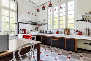 A kitchen with white and black tiled walls, a wooden table, and a red appliance.