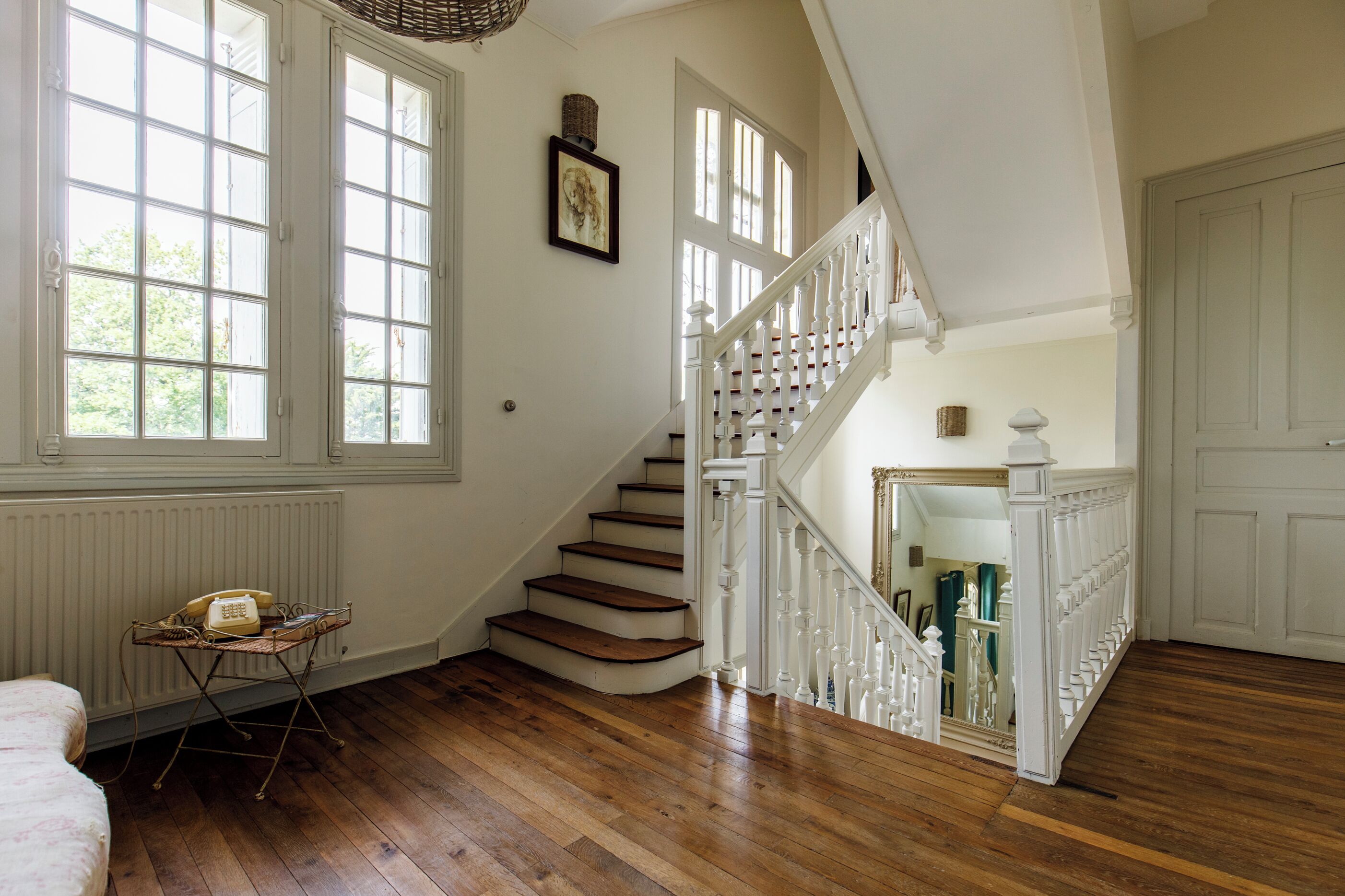 A staircase with white railings and wooden steps, a radiator, and a vintage telephone on a metal stand.