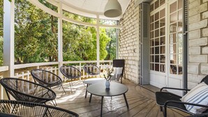 A covered patio with wicker chairs, a table, and a hanging light fixture.