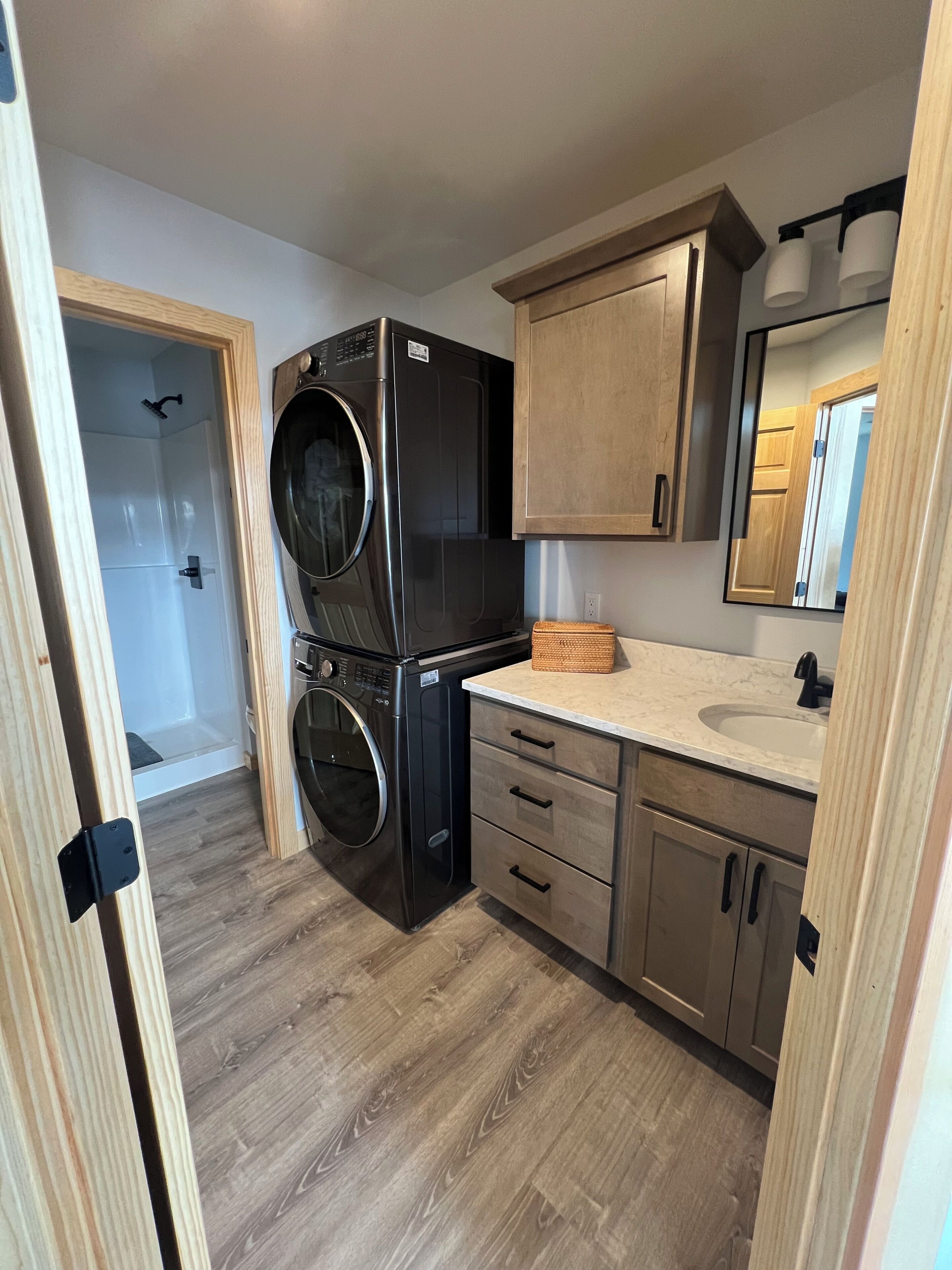 A compact kitchen with a built-in washer and dryer, wooden cabinets, a sink, and a mirror.