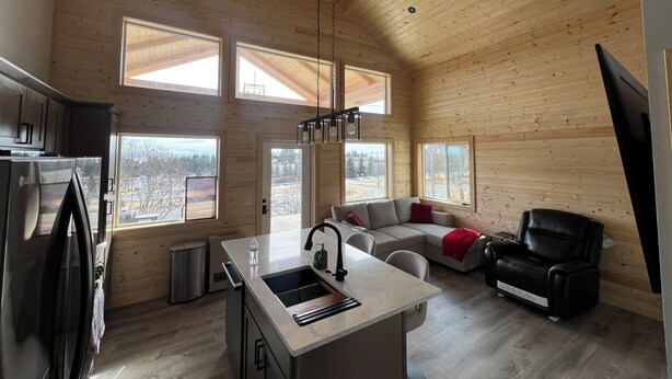 Une cabine spacieuse comprenant une cuisine, un coin repas et un espace salon, avec de grandes fenêtres et un plafond haut.