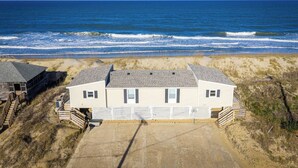Ein Strandhaus mit Kiesweg, Holzterrasse und Blick auf den Ozean.