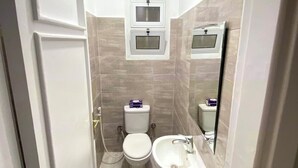 Ein kleines Badezimmer mit Toilette, Waschbecken und einem Fenster über der Toilette.