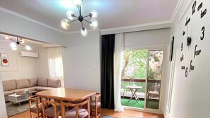 Ein geräumiger Wohnbereich mit einem Holzesstisch, einer Couch und einem großen Fenster mit Blick auf Grünflächen.