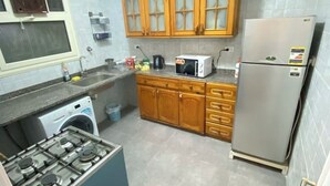 Eine kompakte Küche mit Gasherd, Waschmaschine, Mikrowelle und Kühlschrank.