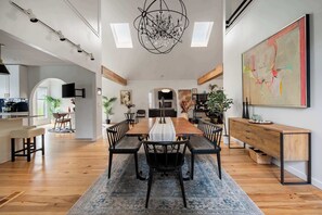 A spacious dining area with a long wooden table, black chairs, and a chandelier.