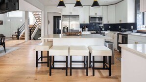 A modern kitchen with a central island, bar stools, and pendant lighting.
