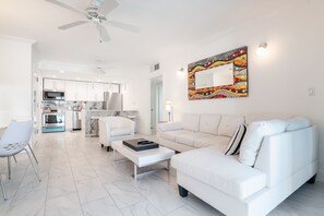 Ein modernes Wohnzimmer mit einem weißen Sofa, einem Couchtisch und einem Essbereich mit Stühlen.
