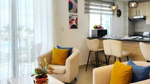 Een moderne woonkamer met een eethoek, keuken en grote ramen.