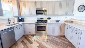 Una cucina con mobili bianchi, un piano cottura in acciaio inossidabile e un forno a microonde.