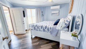 Una camera da letto con un letto, un comodino, uno specchio e una finestra con tende.