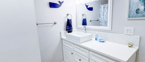A bathroom with a white sink, a mirror, a towel rack, and a blue towel.