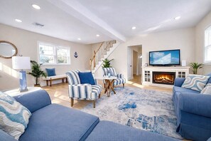 A living room with a fireplace, a television, and striped furniture.